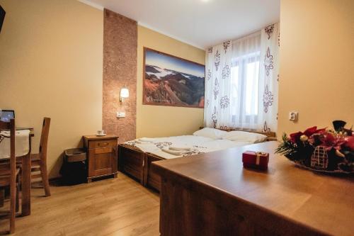 a bedroom with a bed and a desk and a window at Dom Wczasowy Na Szczycie in Zakopane