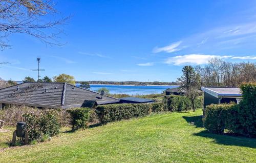 a yard with a house and a lake in the background at Stunning Home In Hundested With Wifi in Hundested