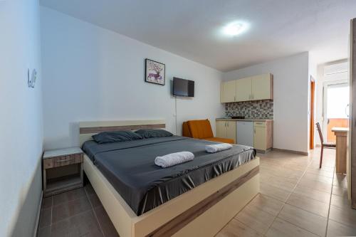 a bedroom with a large bed and a kitchen at Benelux Apartments Bar in Šušanj