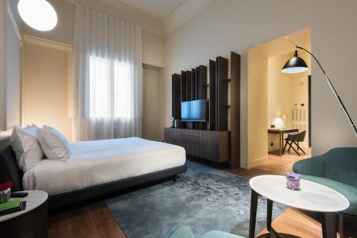 um quarto de hotel com uma cama e uma televisão em Hotel Mercer Sevilla em Sevilha