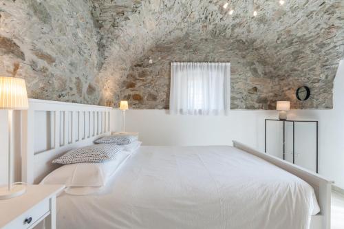 a bedroom with a white bed and a stone wall at Ambiente 90 in Levico Terme