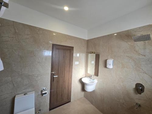 a bathroom with a wooden door and a sink at AdaraResidency in Trivandrum