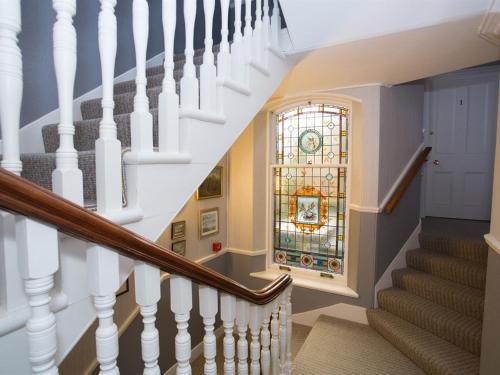 a staircase with white railings and a stained glass window at Arduthie House in Stonehaven