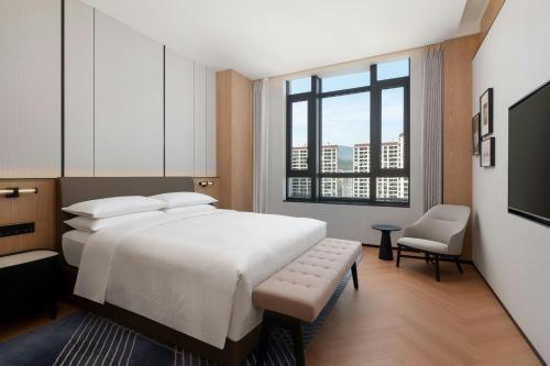 a bedroom with a bed and a chair and a window at Four Points by Sheraton Qingtian in Qingtian