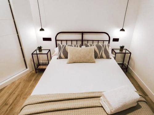 a bedroom with a large white bed with pillows at Apartamentos Casa Miguel in Andújar