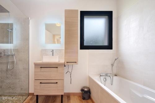 a bathroom with a tub and a sink and a mirror at Maison Peyrelade in Coulounieix-Chamiers