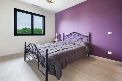 a bedroom with a bed with purple walls and a window at Maison Peyrelade in Coulounieix-Chamiers