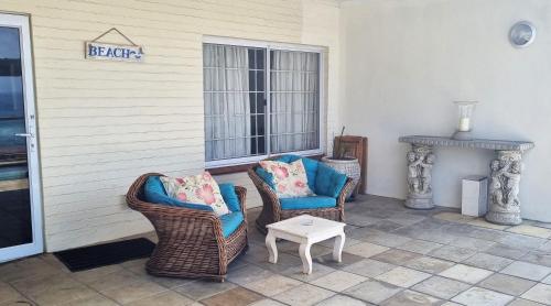a porch with two chairs and a table and a fireplace at Galene Guest House in Port Shepstone