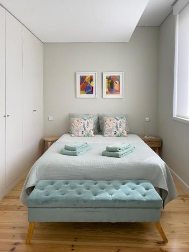 a white bedroom with a large bed with a blue bench at Allegro Patio House in Porto