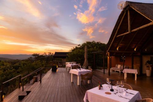 a deck with tables and chairs and a sunset at Elephants Crossing in Welgevonden Game Reserve