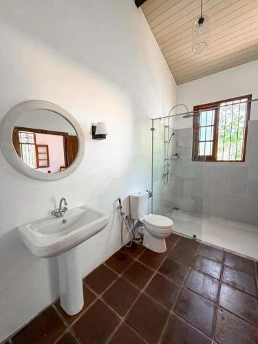 a bathroom with a sink and a toilet and a mirror at The Surveyor's Bungalow in Udugampola