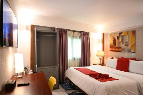 a hotel room with a large bed and a desk at GRAND Hôtel Akwa in Douala