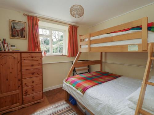 a bedroom with two bunk beds and a dresser at Tyn Y Fron in Llanrhystyd