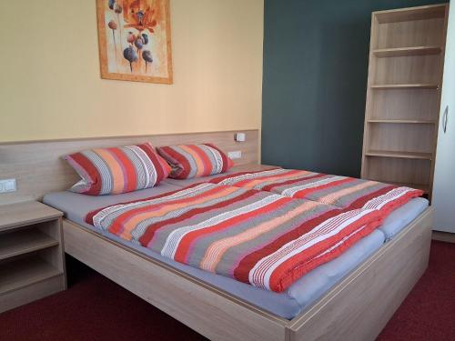 a bed with a colorful striped comforter in a bedroom at Pension Hösl in Mitterteich