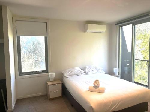 a bedroom with a bed and two windows at Docklands Serenity in Melbourne
