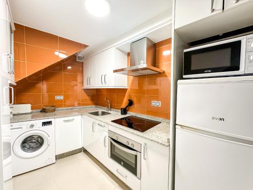 a kitchen with white appliances and orange tiles at Casa das Faluchas by ALÔGA in Finisterre