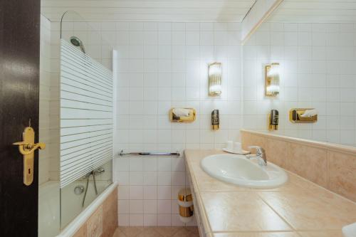 ein weißes Badezimmer mit Waschbecken und Dusche in der Unterkunft Hotel Pfeifer in Gaschurn