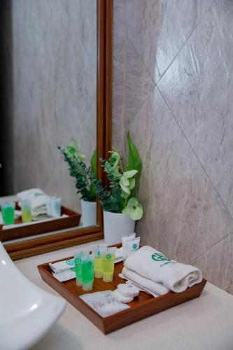 eine Badezimmerablage mit einem Tablett mit Handtüchern und Gläsern in der Unterkunft Greenside Hotel in Arusha