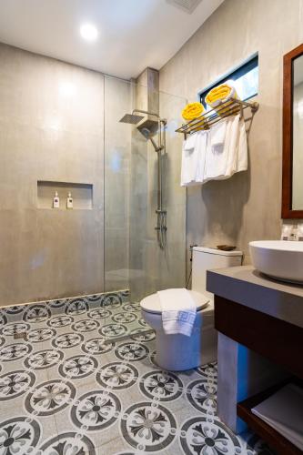 a bathroom with a shower and a toilet and a sink at UNWND Boutique Hotel Camiguin in Mambajao