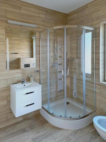 a bathroom with a shower and a toilet and a sink at Domki i Apartamenty WiR na Kaszubach in Chmielno
