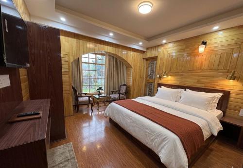 a bedroom with a large bed and a desk at Hotel The Apple Estate in Pahalgām