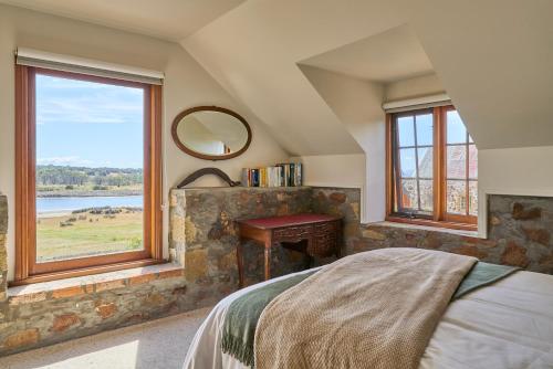a bedroom with a bed and a large window at Blacksmith's Cottage at Lisdillon Estate in Little Swanport