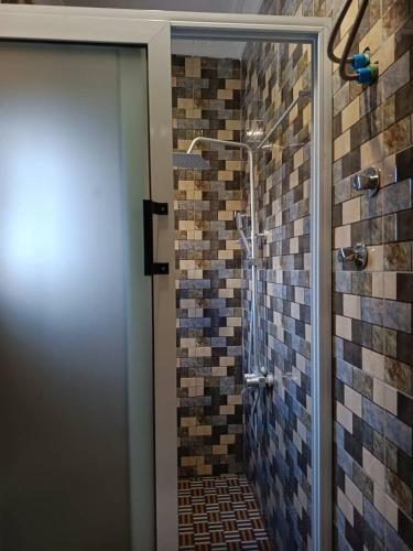 a bathroom with a shower with tiles on the wall at Trapezium Lodge in Amasaman