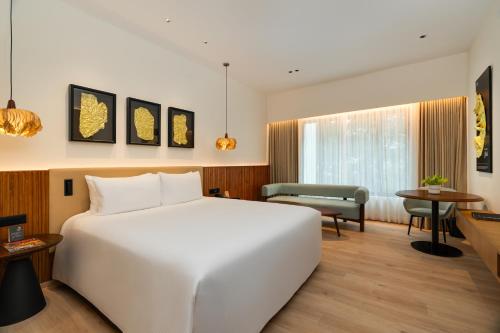a bedroom with a large white bed and a living room at Marigold Hotel in Hyderabad