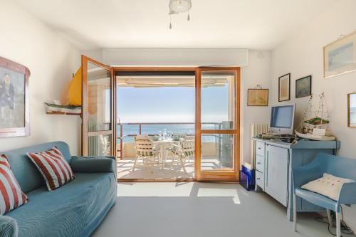 a living room with a blue couch and a view of the ocean at Fronte mare con parcheggio! in Grado