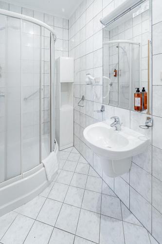 a white bathroom with a sink and a shower at Hotel Senator in Dźwirzyno