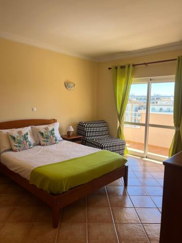 a bedroom with a bed and a chair and a window at Apart. Arco-Iris - Amazing view in Lagos