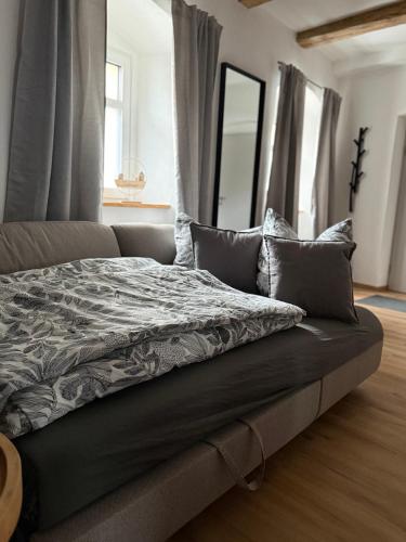 a bed with a gray blanket and pillows on it at Wohnzeit by Zirwick Apartment in Windischeschenbach