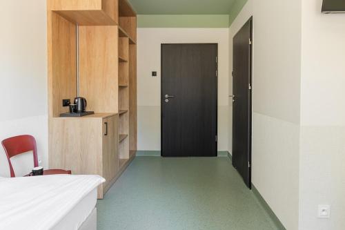 a hallway with a black door and a room with green floors at Hostel Rest in Krakow