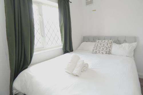 a bed with white sheets and pillows and a window at The Linwood Terrace in Eastwood