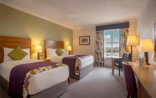 a hotel room with two beds and a desk at Maldron Hotel & Leisure Centre, Oranmore Galway in Oranmore