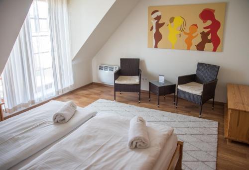 a bedroom with a bed and two chairs and a painting at Apartmán Říčky 23 in Říčky