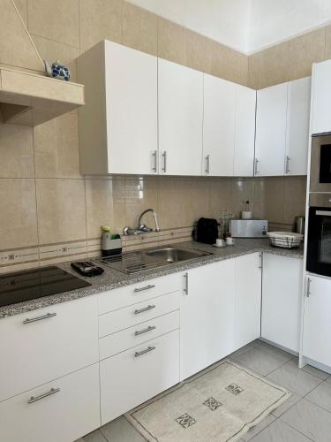 a kitchen with white cabinets and a sink at Pina House in Pêra