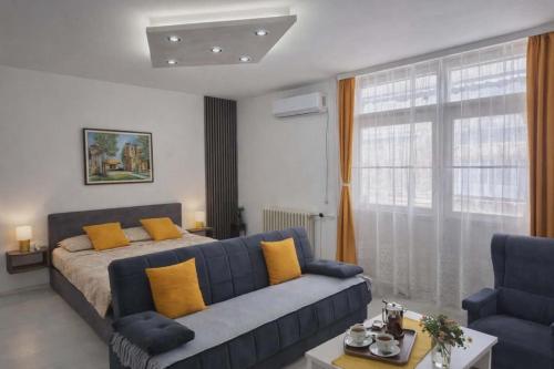 a living room with a blue couch and a bed at Globus in Kruševac