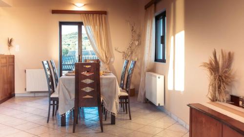 a dining room with a table and chairs and a window at Ocean Breeze Apartment - Panoramic Sea View & Olive Grove - 100m to Beach in Kypseli
