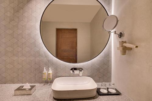 a bathroom with a round mirror and a sink at Lemon Tree Premier, Biratnagar, Nepal in Biratnagar