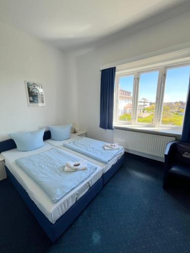a bedroom with two beds and two windows at Strandhotel Sylt Wenningstedt in Wenningstedt