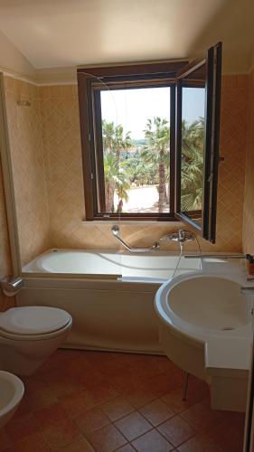 a bathroom with a tub and a toilet and a window at Villa Demetra Resort in San Leone
