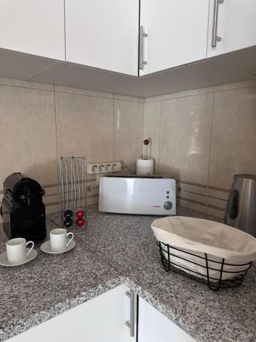 a kitchen with a counter with cups and a microwave at Pina House in Pêra