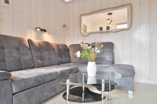 a living room with a couch and a table with flowers at Bungalow Nebel Nr 3 in Kellenhusen