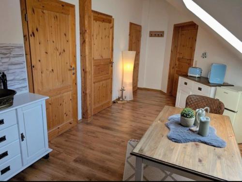 a room with a table and a kitchen with wooden floors at Nicht Daheim und doch Zuhaus in Heiligenhafen