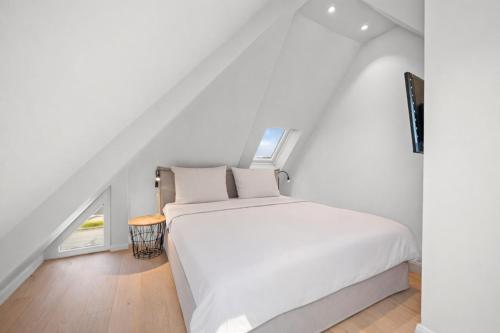 a white bedroom with a white bed and a window at Traumloft Wenningstedt in Wenningstedt
