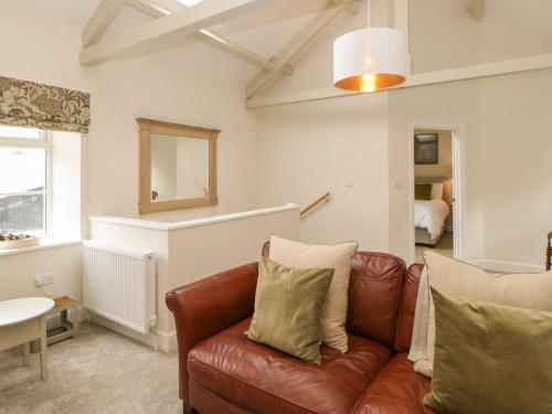 a living room with a leather couch and a mirror at Dairy Cottage in Kirkby Stephen
