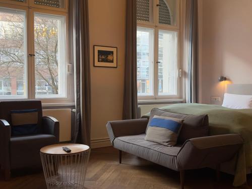 a bedroom with a bed and a couch and windows at Wil7 Boutique Hotel in Berlin