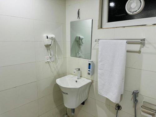a white bathroom with a sink and a mirror at Koll Hotel in Erbil