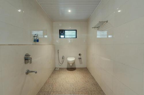 a bathroom with a toilet and a shower in it at Shoolin Resorts in Manipal